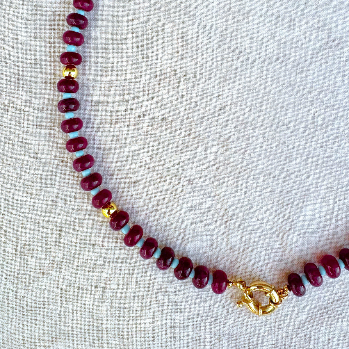 Close-up of Violetta necklace featuring burgundy jade beads and gold-plated details